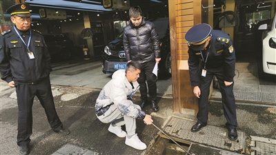 执法人员检查洗车店排水沉淀设施。.jpg