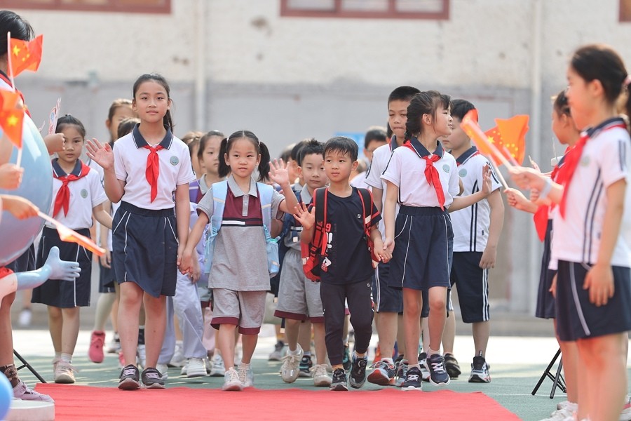 复兴东路第三小学高年级学生牵着一年级弟弟妹妹踏上红毯进入校园。记者 赖鑫琳 摄.jpg