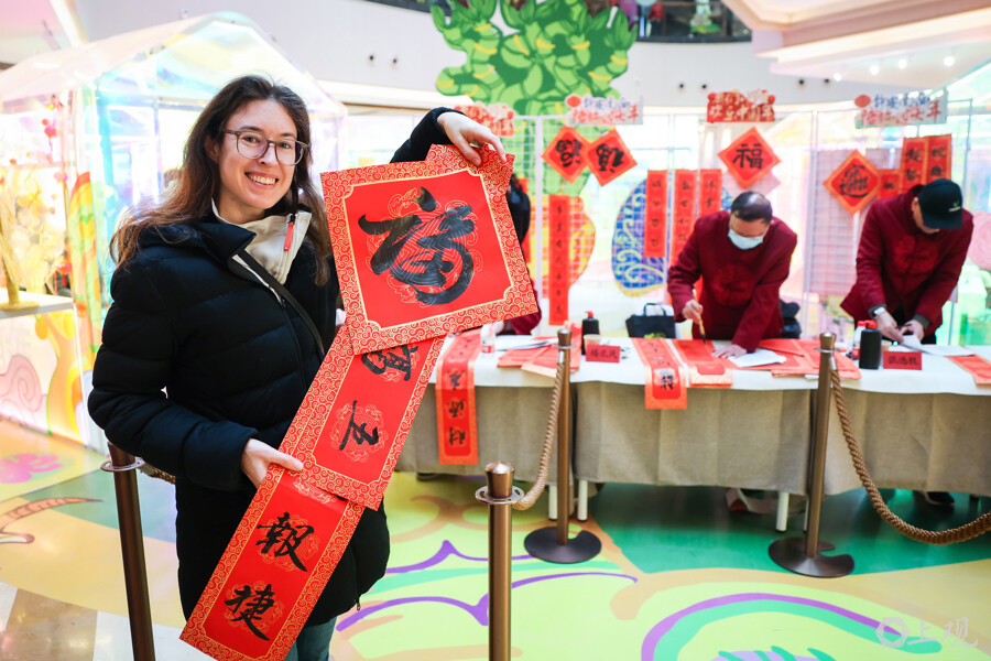 來自德國的游客展示自己心儀的春聯(lián)和福字.jpg